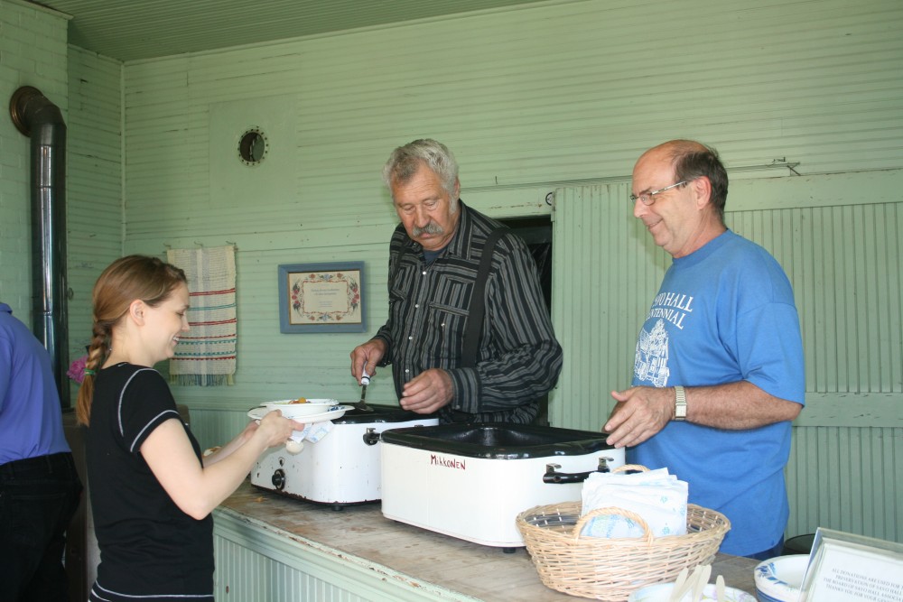 Jim Dumire, center, and Calvin Raisanen serve mojakka (stew) to Marianne Marttila-Klipfel at Savo Hall during Finn Fest 2013.